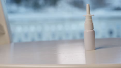 nasal spray bottle pushed and falling onto white surface table, slow motion