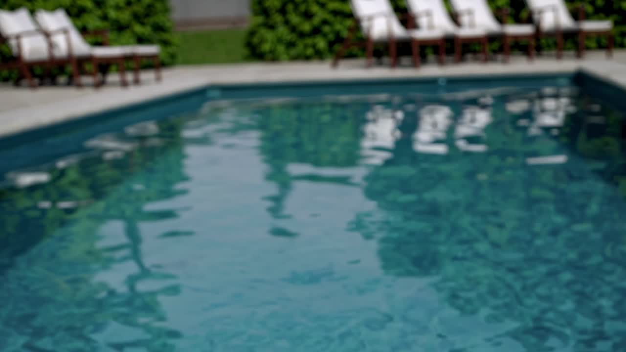 Sløret videobillede af en fredfyldt pool med liggestole, fanget fra en lav vinkel