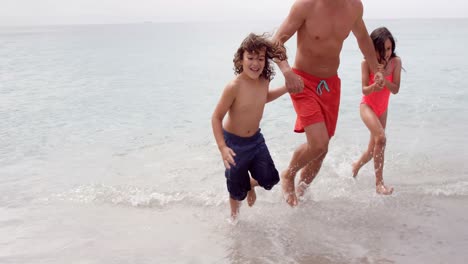 Padre-E-Hijos-Corriendo-Fuera-Del-Mar