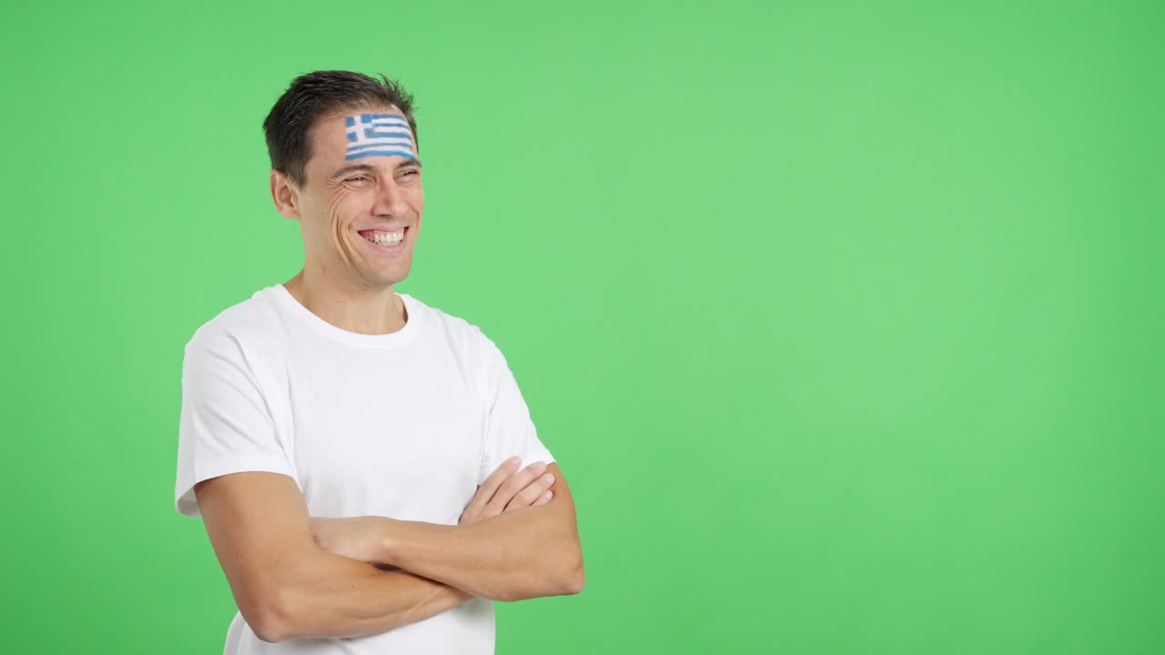 Happy man with greek flag painted on face looking away