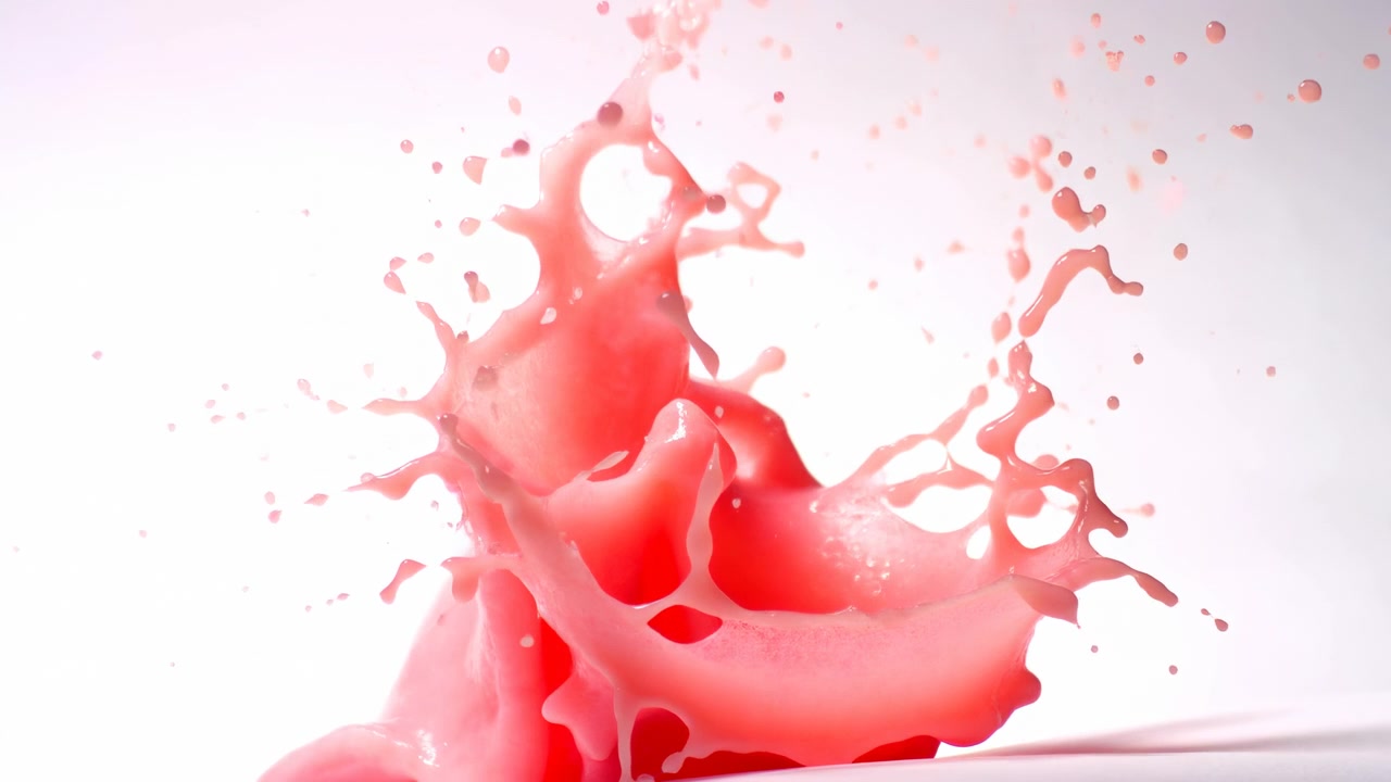 Bright red liquid erupts upward from the lower center against a clean white background, forming a dramatic splash with translucent droplets, fluid motion