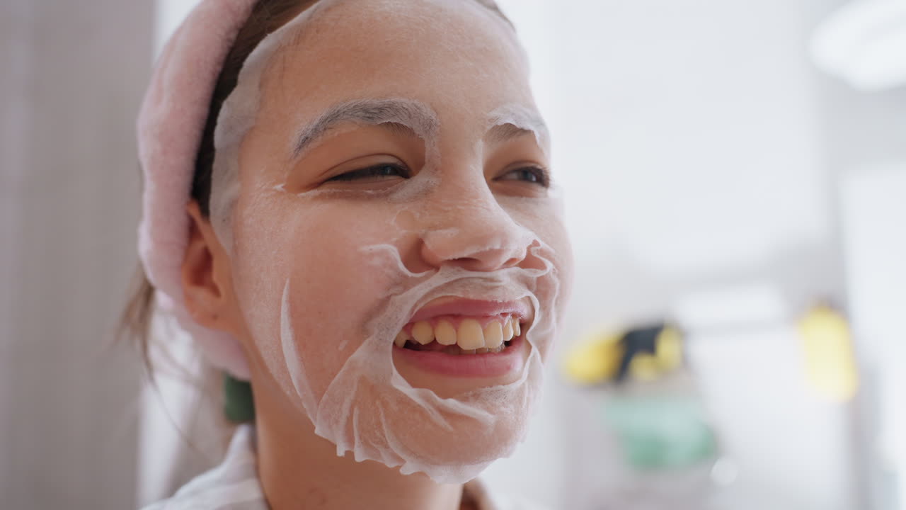 Young Woman With Foaming Facial Laughing, Pink Headband, Morning Bathroom Mirror, Gentle Cleanser Lather On Cheeks, Playful SelfCare, Bright Natural Light, Moisturizing Towel Nearby