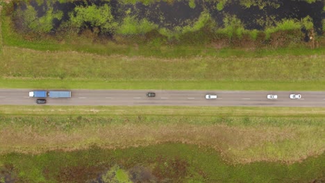 Flying-above-the-road-in-the-rural-neighbourhood,-where-lots-of-cars-and-trucking-are-rolling