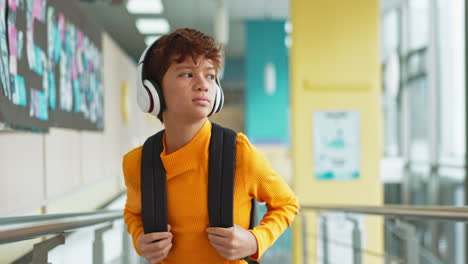 boy with headphones and backpack in school hallway