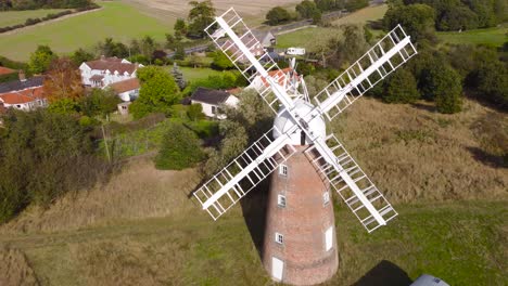 flying over billingford windmill at a farmland area with house in diss, norfolk - aerial drone backward shot