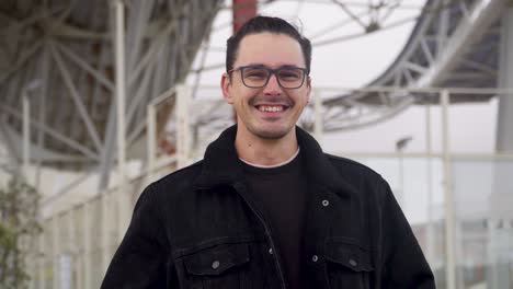 portrait of a cheerful, smiling young man wearing a black jacket and glasses