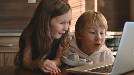 excited little girl and boy using a laptop and having fun at home