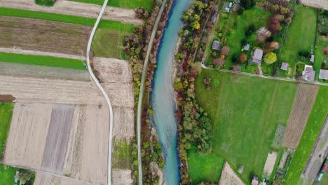 toma cinematográfica de drones mirando directamente hacia abajo en un río rodeado de naturaleza y tierras de cultivo