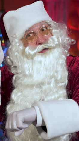 santa claus in christmas decorated room. old santa with white beard at home coming to the window at christmas night. vertical video