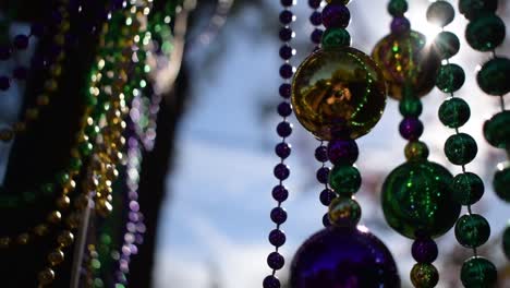 sunny outdoor mardi gras beads on light post in sunshine blowing in wind