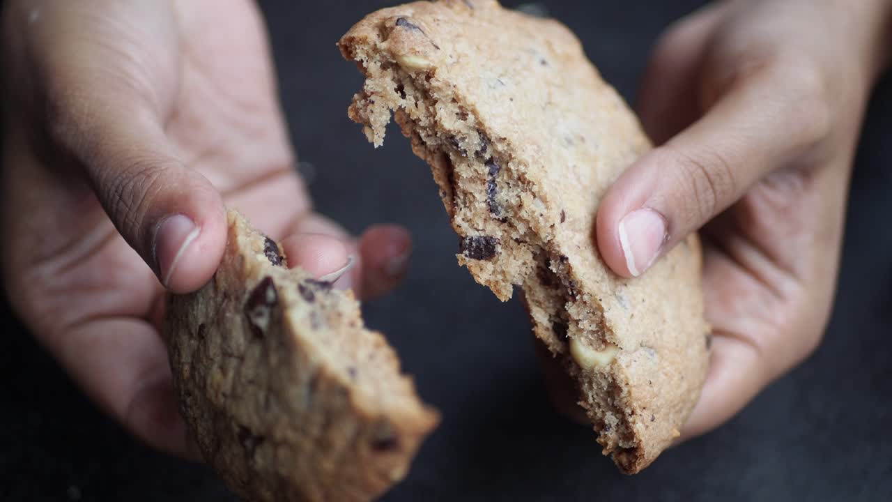 Hands Holding a Broken Chocolate Chip Cookie