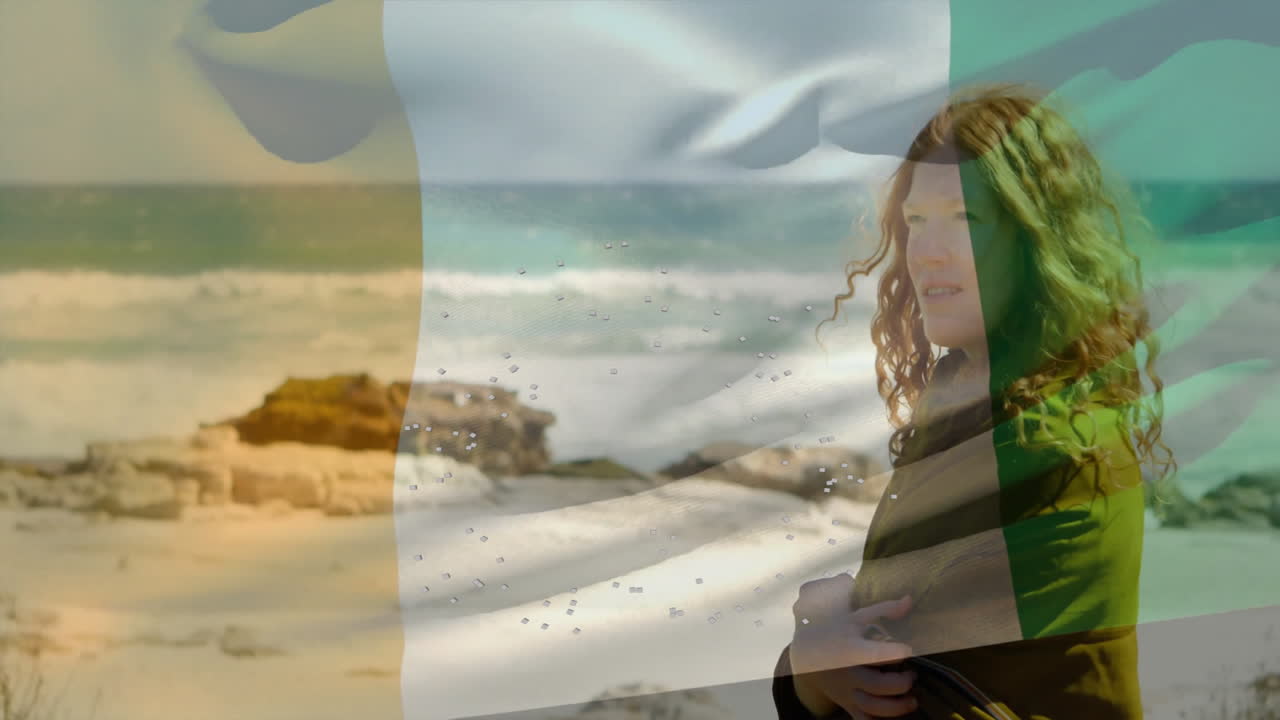 Standing by ocean, woman with curly hair and animation of Irish flag