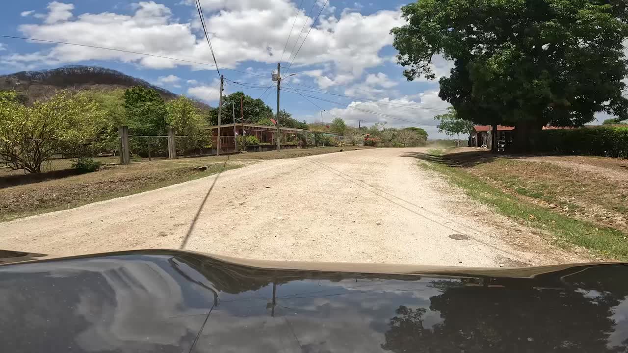 vehículo gris que avanza por un camino de tierra en la zona rural de costa rica y luego se detiene cerca de la granja, disparo en el capó delantero