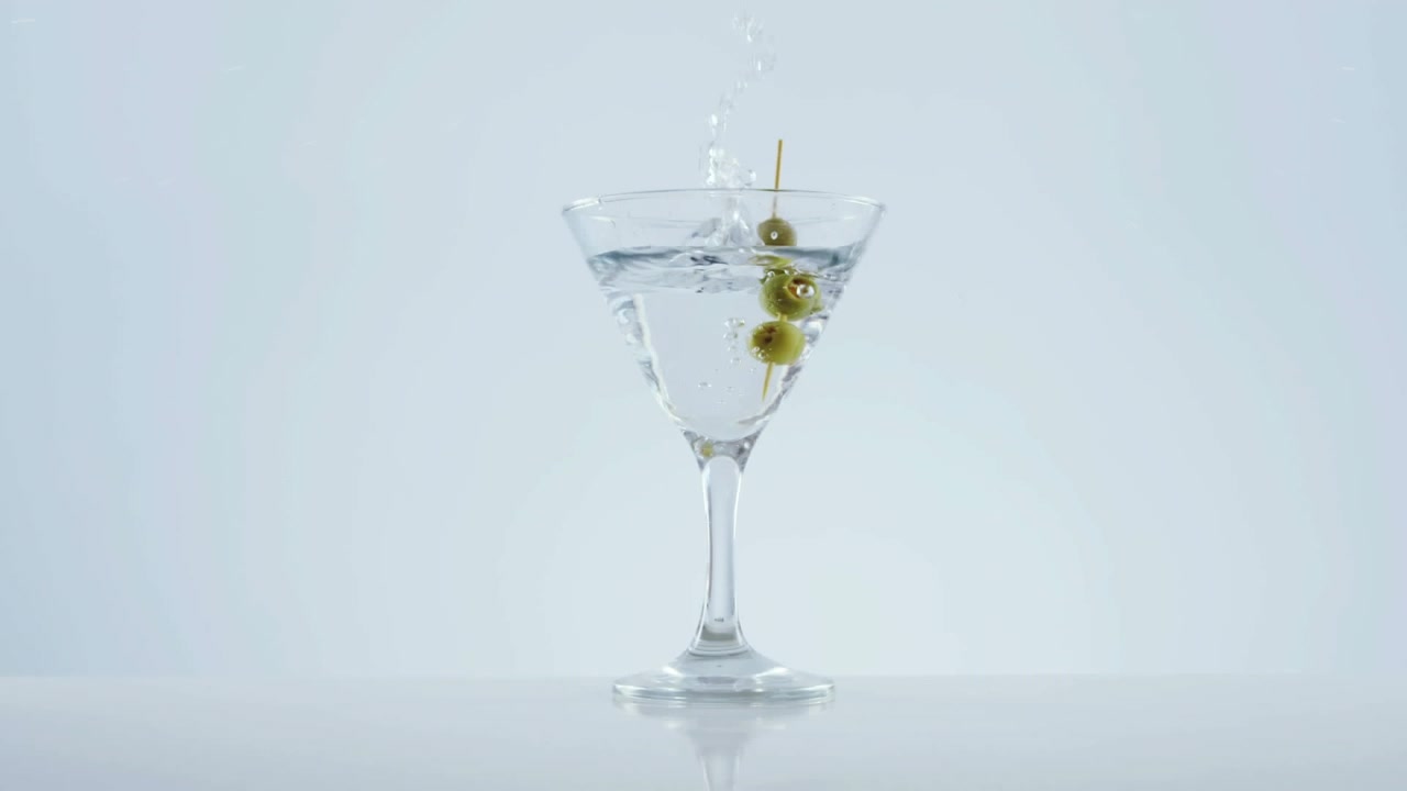Animazione di puntini rossi che si muovono su un bicchiere da cocktail con olive su sfondo bianco.