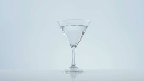 animation of red specks moving over cocktail glass with olives on white background