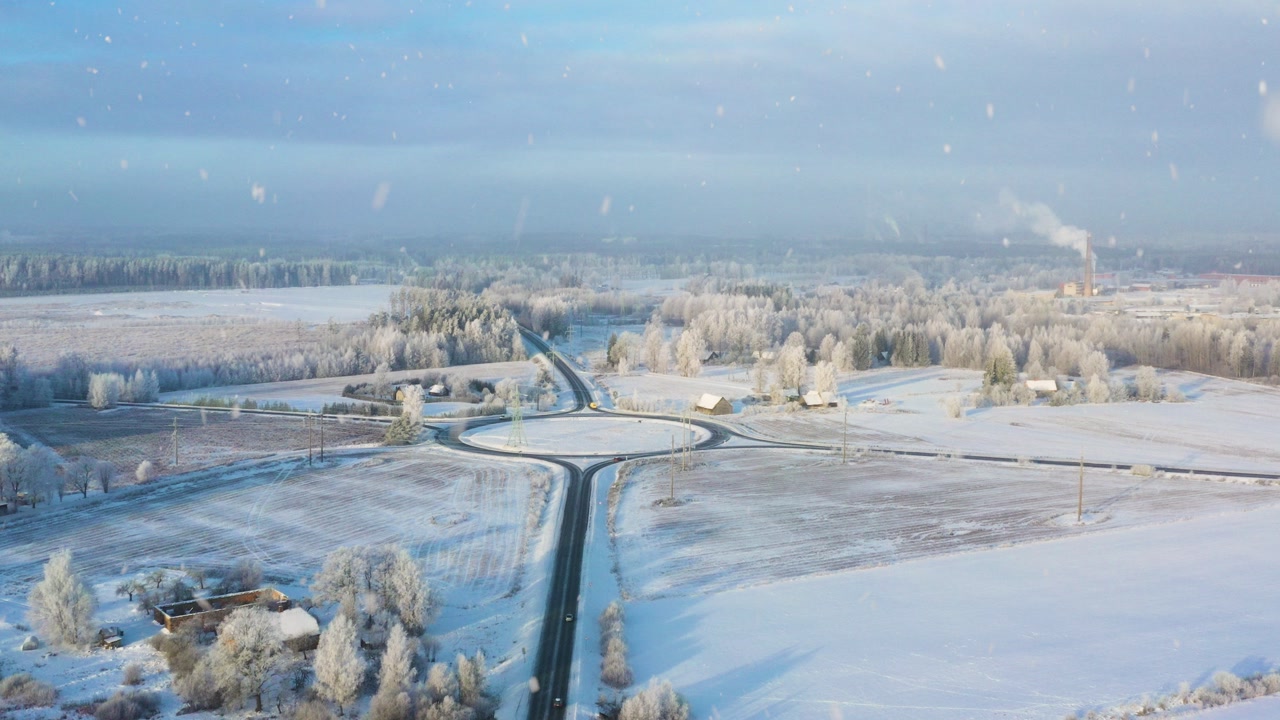 Winter morning aerial with roundabout road intersection and falling snow