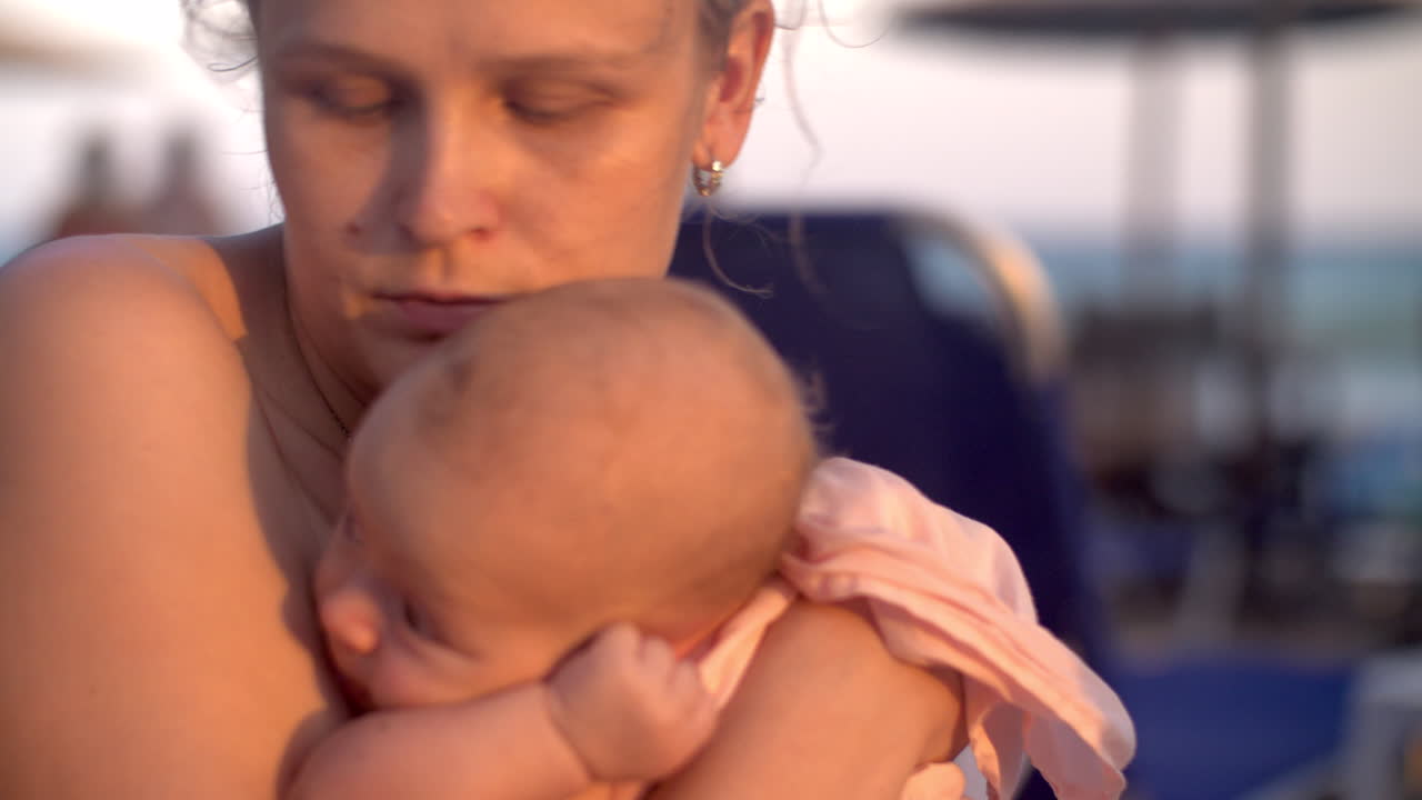 Mama mit Baby am Strand bei Sonnenuntergang