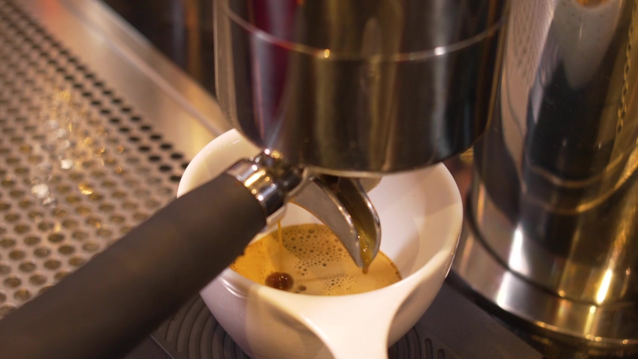 Processo artigianale di preparazione dell'espresso con portafiltro e tazza bianca in una moderna caffetteria specializzata.