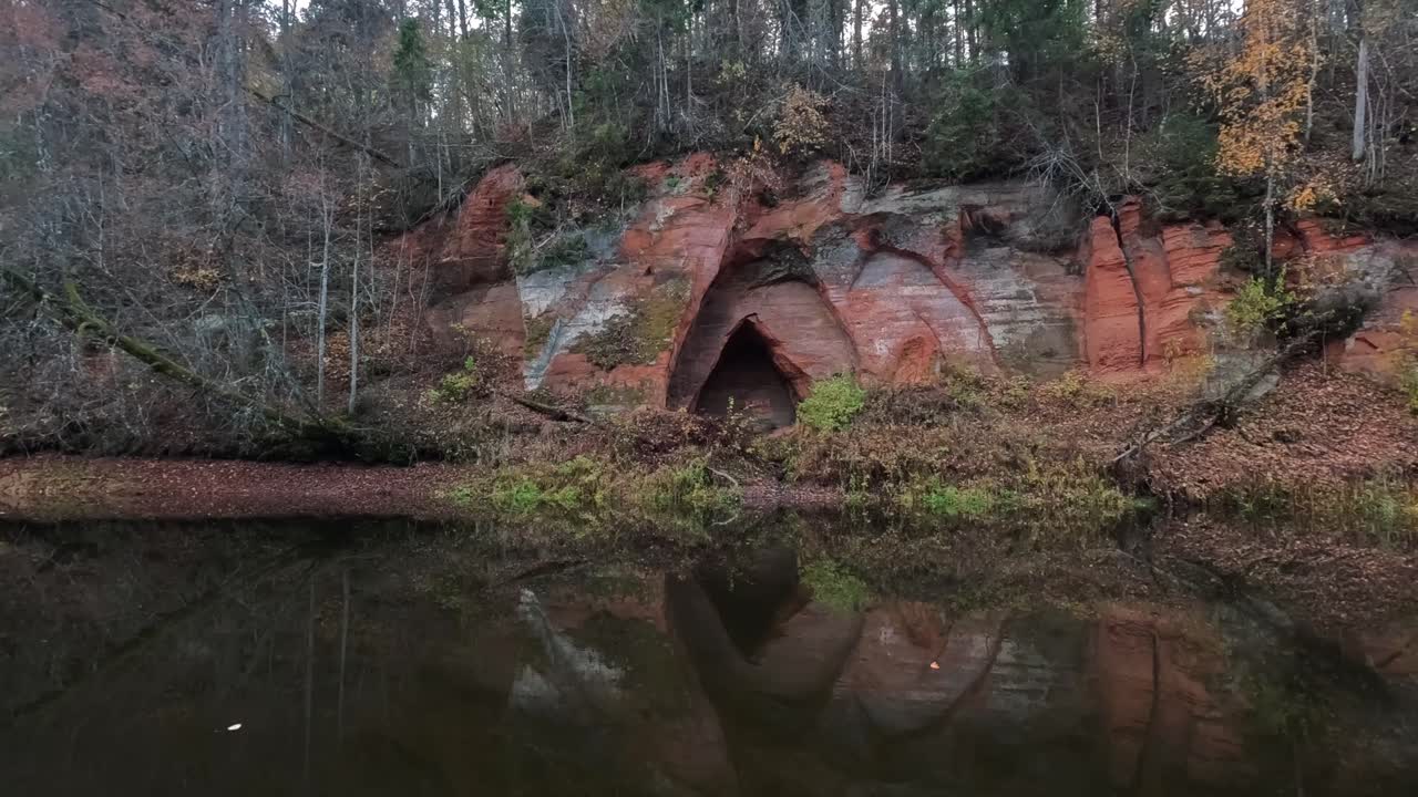Englegrotten, en rød sandstensklippe formet som englevinger, ved floden Salaca i Skanaiskalns Naturpark i Mazsalaca, Letland, efterår