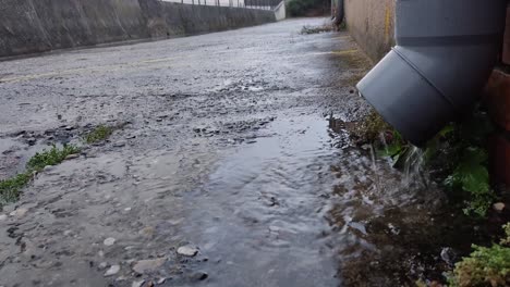 Blick-Auf-Regenwasser,-Das-Nach-Einem-Sturm-Aus-Einem-Rohr-Eines-Gebäudes-Auf-Die-Straße-Fällt