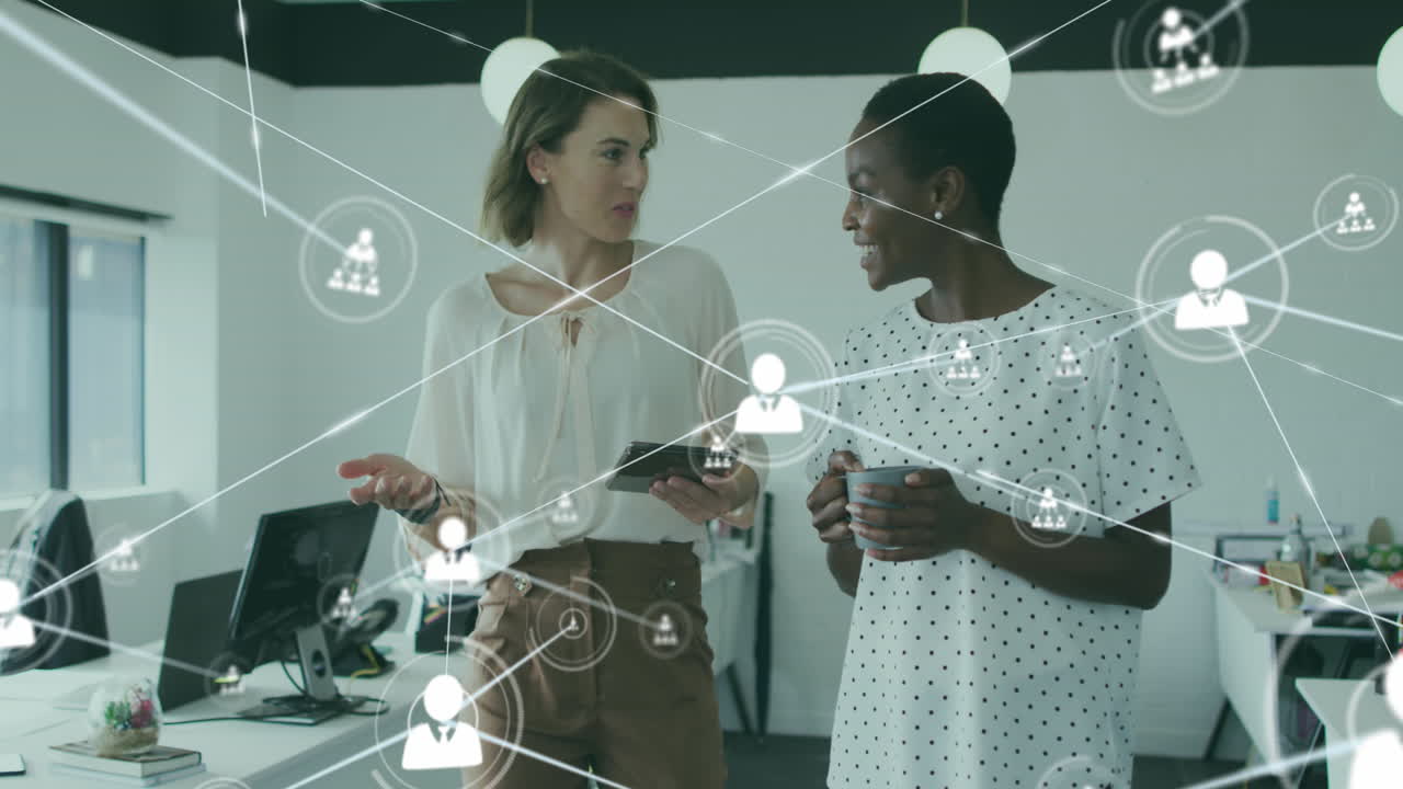 Animation of connected icons over diverse female coworkers walking and sharing ideas in office