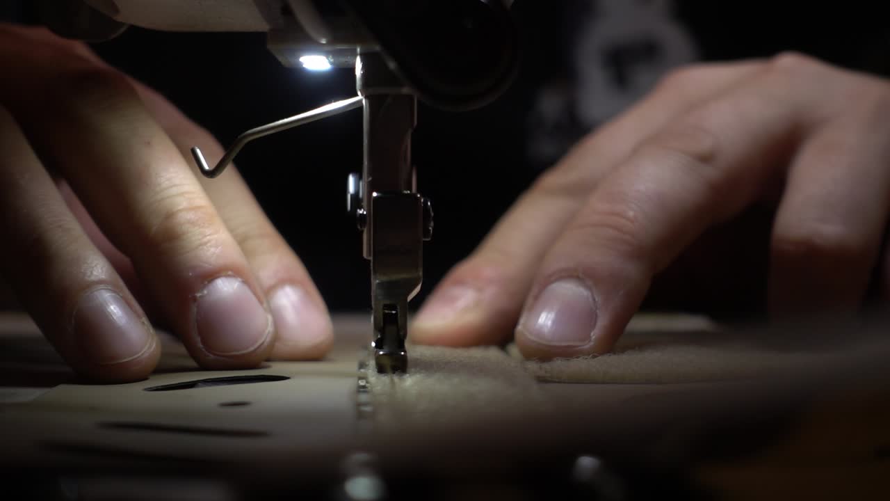 Slowmotion of a man making a military costume on the very complex sewing machine