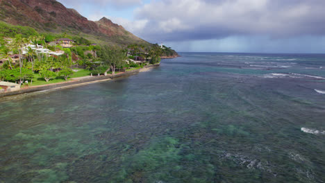 drone footage along the island coast of oahu hawaii with coral reefs showing through the crystal clear water of the pacific ocean near honolulu