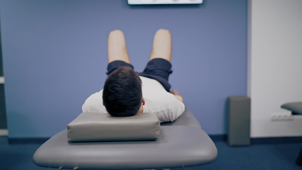 Young man is lying on massage table in a medical clinic. Patient on the bed in hospital. Physical therapy concept