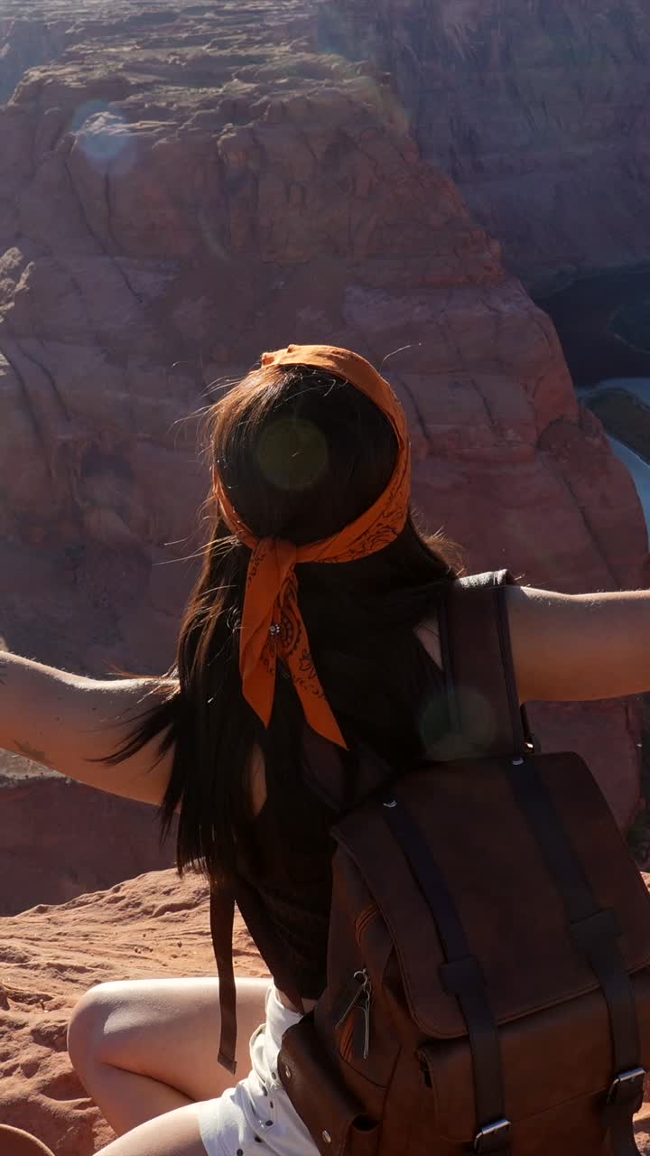 Donna felice seduta sul ciglio di un dirupo con vista su un canyon