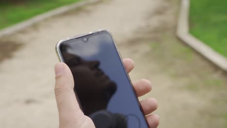 Reflection-of-man-on-mobile,-looks-at-the-sky-and-then-touches-the-screen-of-his-mobile-phone