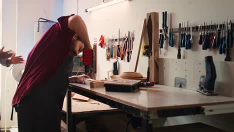 woodworker in assembly shop using power drill to create holes