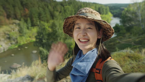 cheerful asian tourist waving and telling about hike