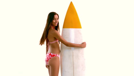 woman next to her surfboard turning and looking at the camera