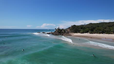 clarkes beach with surfers floating in the ocean in new south wales, australia - drone shot