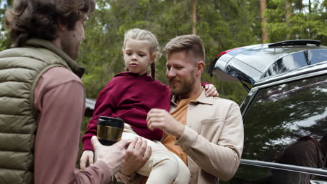 family outside big black car before travelling