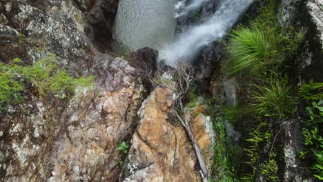 slow reveal of water cascading down a rock formation into a secluded natural swimming hole