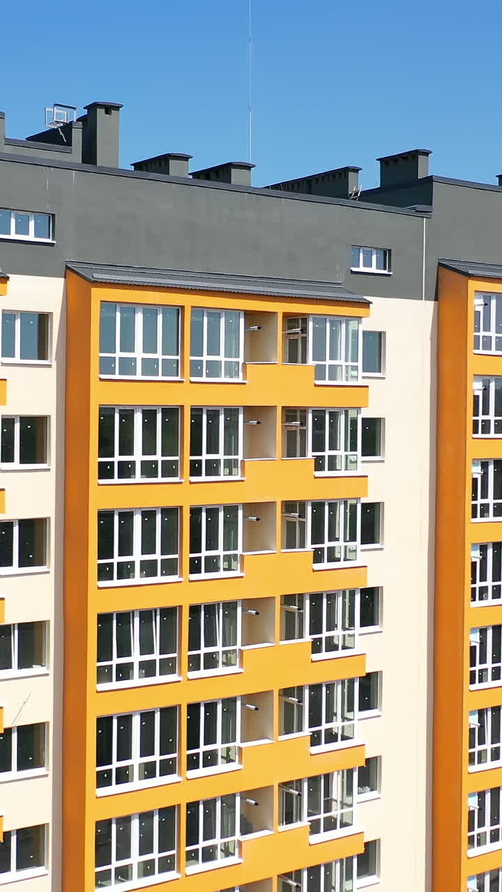 Facade of a new house for city residents. Modern apartment building with large windows and colorful walls in sunny summer day. Vertical video