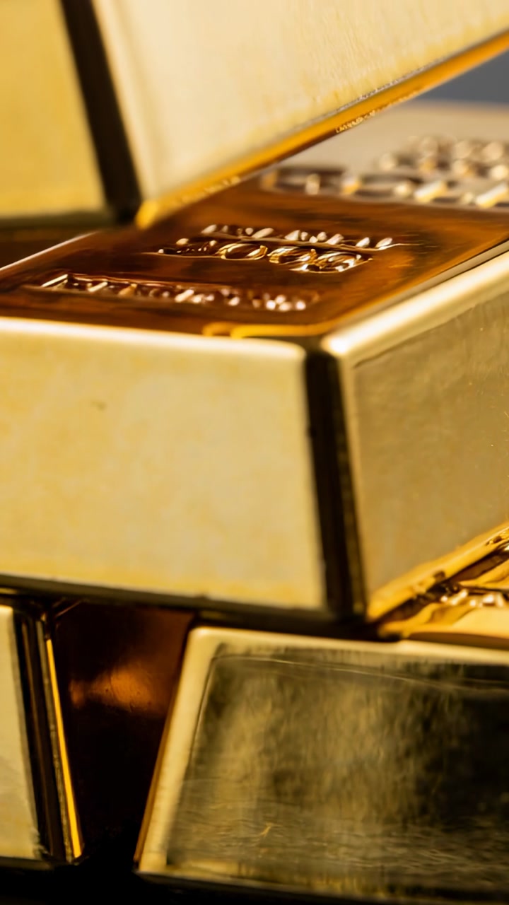 Vertical video: Tilting gold bars on glass table as fingertip lifting top bar showing stamp