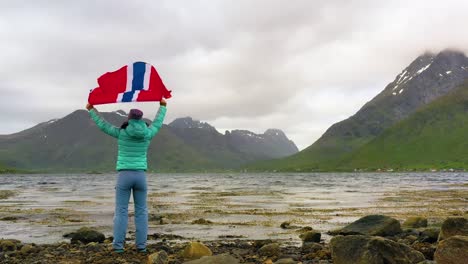 woman with a waving flag of norway on the background of nature