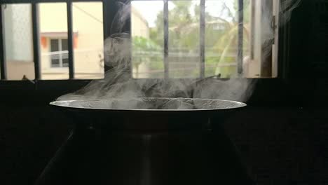 Pot-cooking-rice-in-a-traditional-way-by-boiling-water-in-a-black-background-with-white-smoke-coming-in-slow-motion