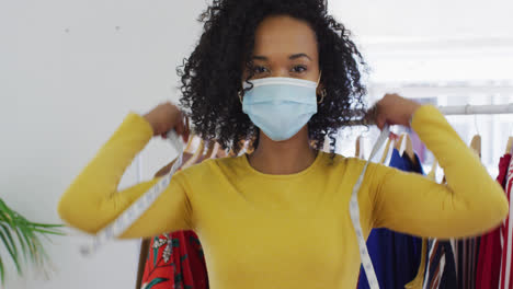 Portrait-of-female-fashion-designer-wearing-face-mask-with-measuring-tape-around-her-neck