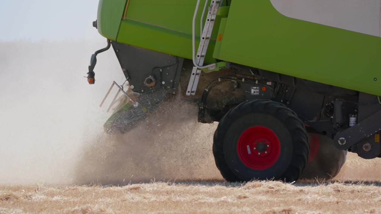 Combine harvester wheel throwing straw and dust