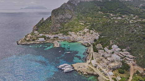 levanzo italy aerial v3 birds eye view drone flyover into the harbor capturing charming coastal island town, rugged cliffs and pristine turquoise bays water - shot with mavic 3 cine - may 2023