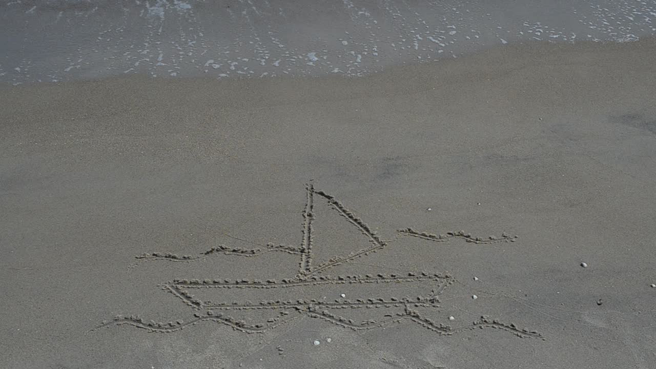Disegno sulla sabbia: barca, onde e gabbiani in primo piano. Scatto sulla spiaggia