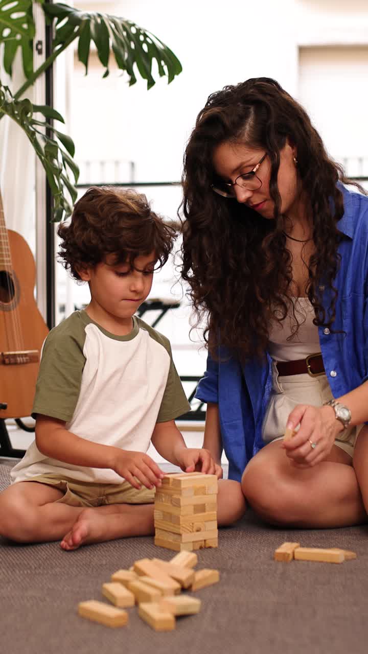 Mother and son playing wooden block game at home