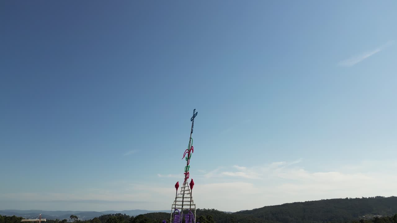 decorative cross structure with scout symbols stands tall against a bright blue sky