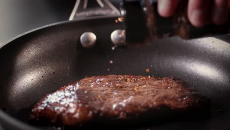 seasoning is poured onto a cut of meat in a frying pan