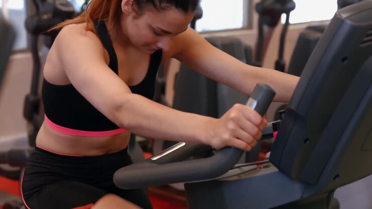 Fit woman using exercise bike in gym