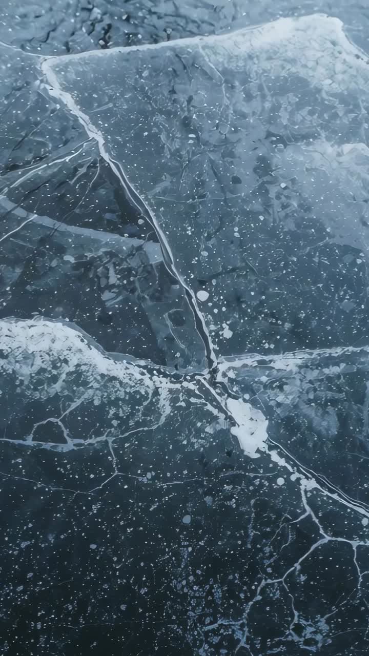 Video verticale: camera in movimento che rivela il ghiaccio incrinato su uno stagno, spostandosi verso le bolle e terminando su una fessura