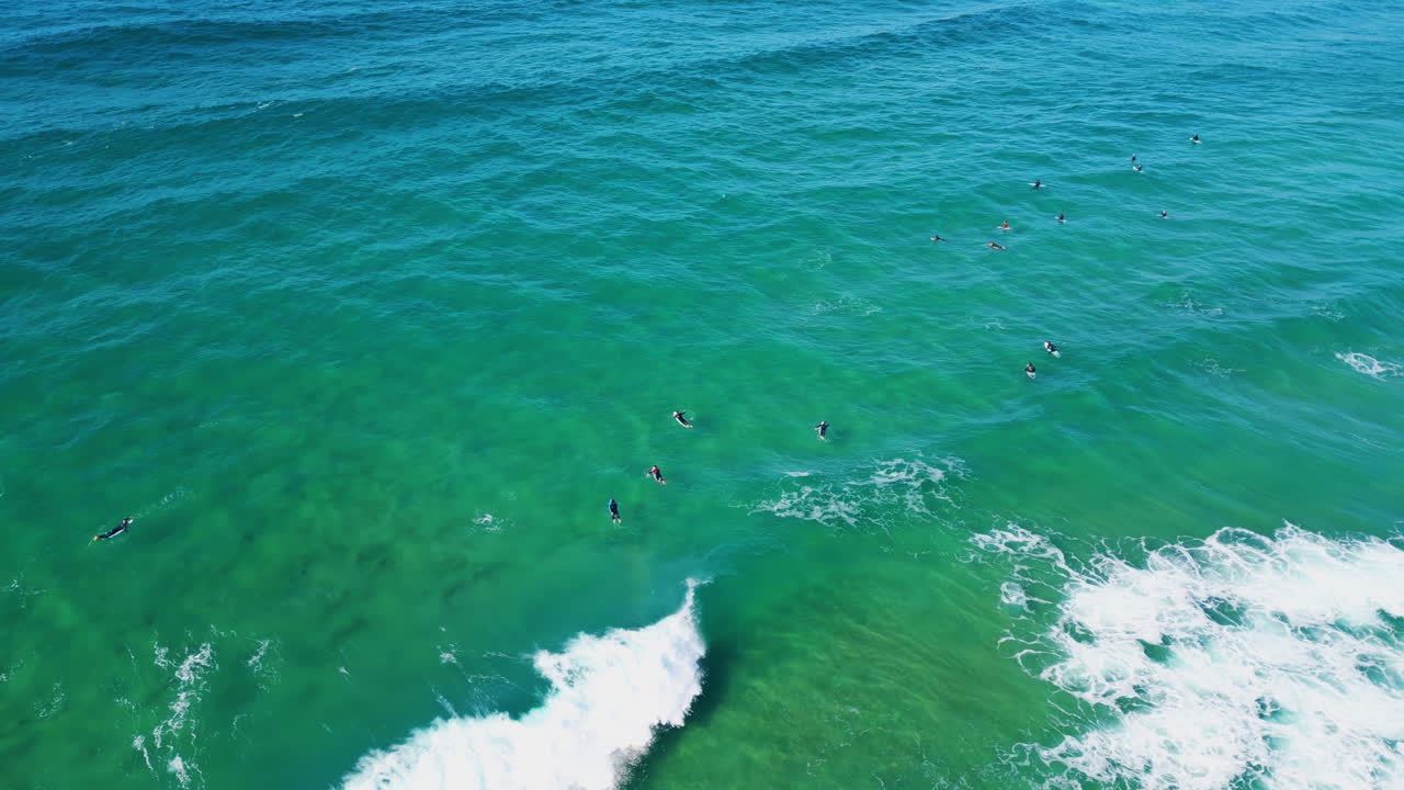 그룹 서퍼들이 바다를 헤엄치고 파도를 기다리고 있습니다. 여름 주말. 바물 굴림.